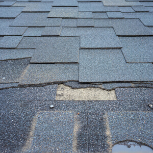 Close Up View Of Bitumen Shingles Roof Damage That Needs Repair.
